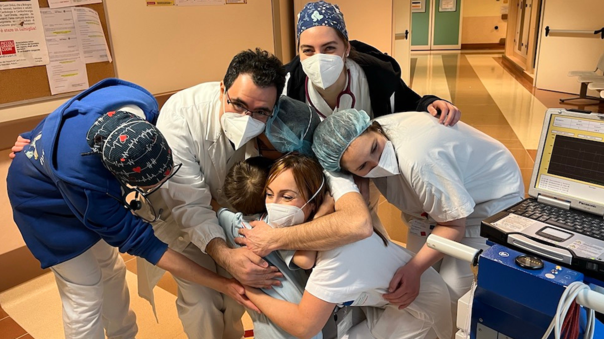 bambino con cuore artificiale abbracciato dal personale sanitario del reparto